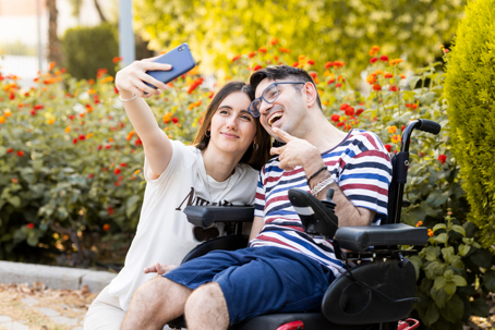 happy man in wheelchair taking a selfie with a woman