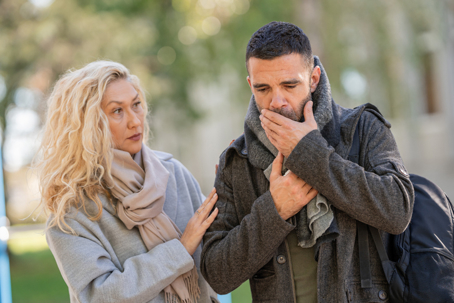 concerned woman helping coughing man